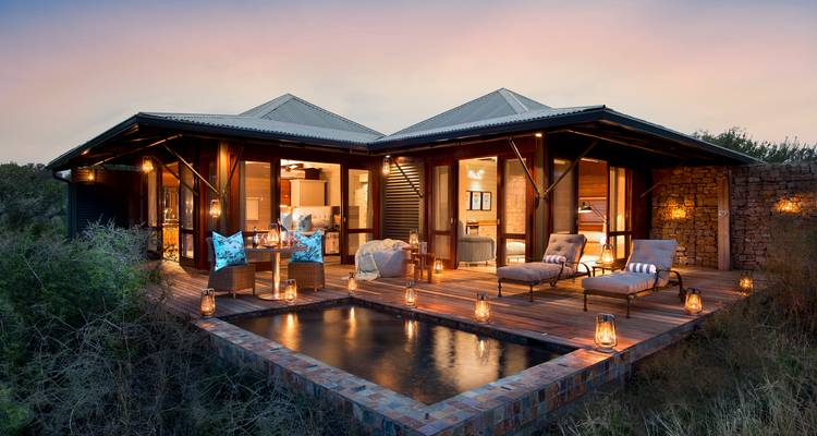 Luxurious bush lodge with private plunge pool and lantern-lit deck at twilight.