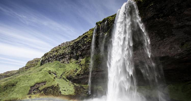 Side view of Seljalandsfoss with bright daylight and mossy cliffs around