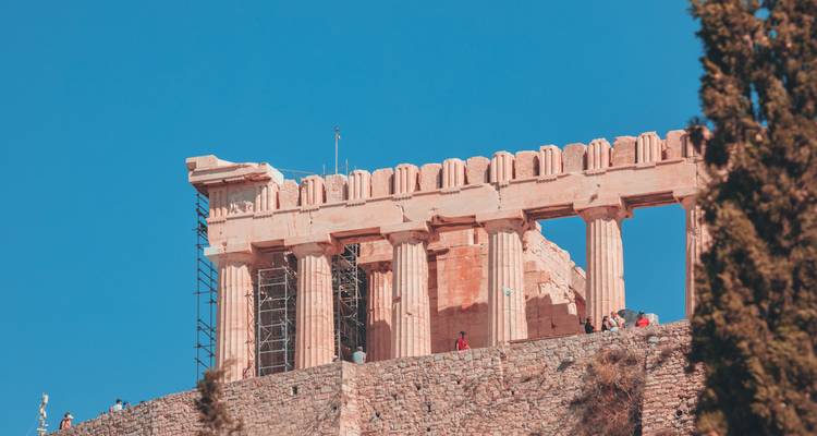 Close-up of the Parthenon columns on the Acropolis with tourists at the base and scaffolding visible.