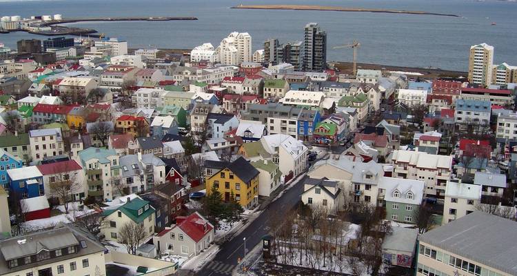 Vista aérea más cercana de las casas coloridas de Reikiavik y la costa con grúas y puerto.