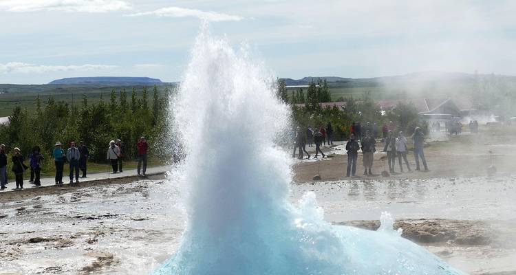 Strokkur geyser erupts high into air while spectators watch from safe distance