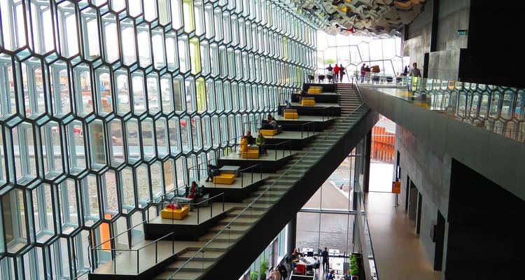 Intérieur de la salle de concert Harpa avec façade en verre géométrique et plateformes de sièges étagées