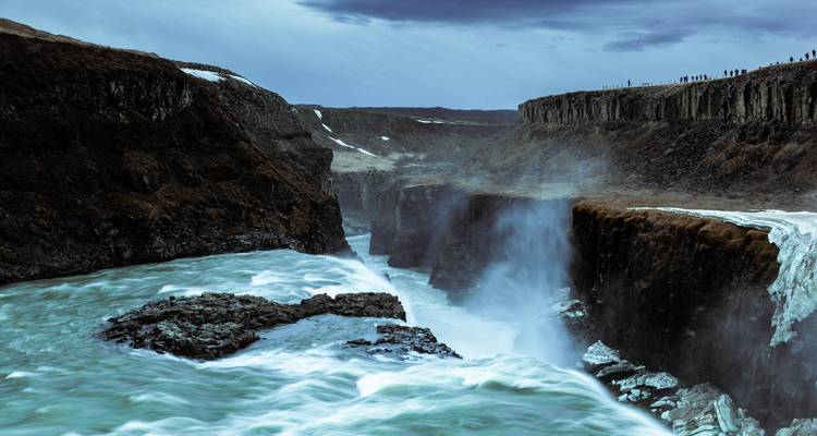 Vue spectaculaire en soirée des gorges de Gullfoss avec brume et rivière bleu-vert profond sous un ciel menaçant