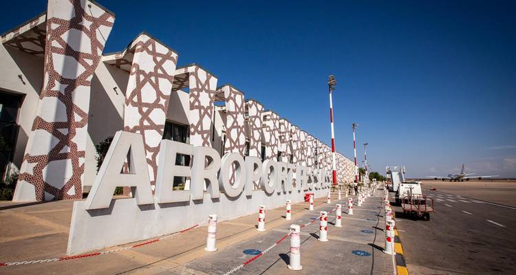 Exterior de la terminal del aeropuerto marroquí con fachada estampada y un gran letrero AEROPORT bajo un cielo despejado