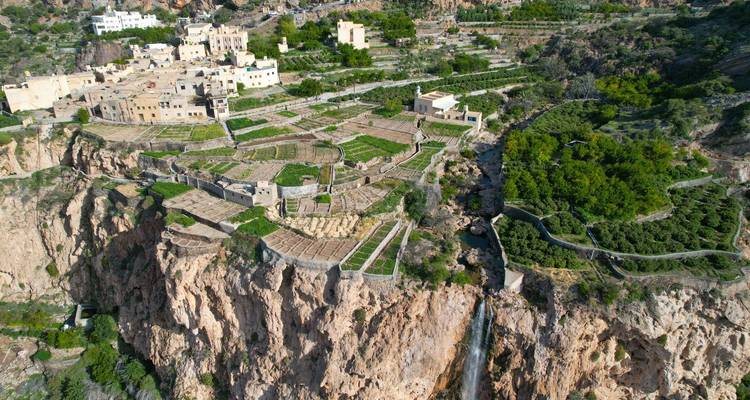 Vue aérienne des fermes en terrasses accrochées aux falaises de Jabal Akhdar avec cascade