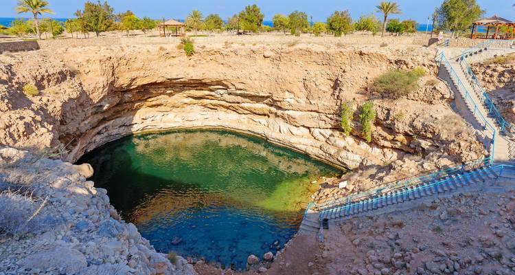 Piscine circulaire turquoise du gouffre de Bimmah encadrée par un paysage désertique rocheux
