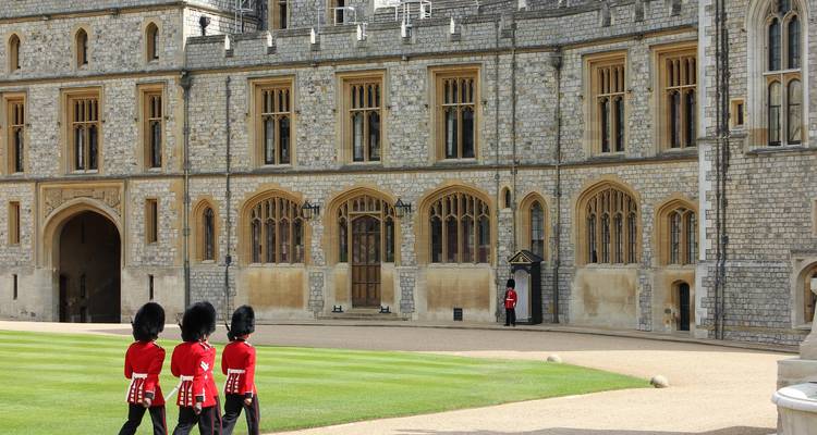 Uniformierte Wachleute in roten Uniformen und Bärenfellmützen marschieren über den Innenhof des Steinplatzes von Schloss Windsor