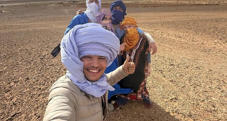 Reizigers met tulbanden glimlachen voor een selfie op een kale woestijnvlakte