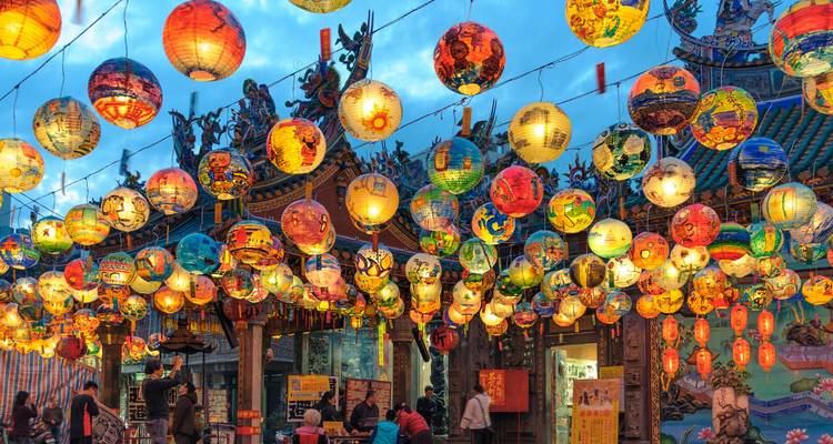Lebendige Straßenszene mit hunderten bunten hängenden Laternen auf einem Nachtmarkt.