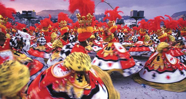 Blurred motion capture of vibrantly costumed samba dancers swirling during Rio Carnival.