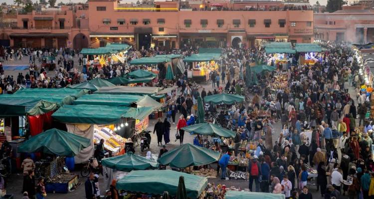 La place animée de Jemaa el-Fnaa remplie d'étals et de foules au crépuscule à Marrakech