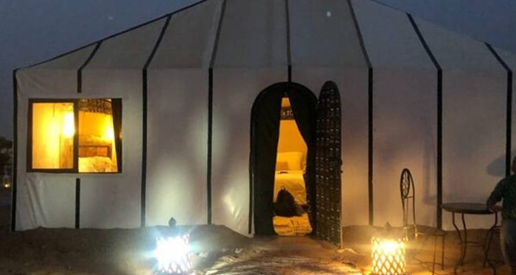 Tente du désert en toile doucement illuminée de l'intérieur la nuit avec des lanternes à l'entrée.