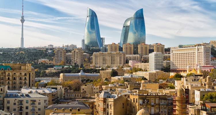 Modern Baku skyline featuring the curving Flame Towers rising above the historic city below.