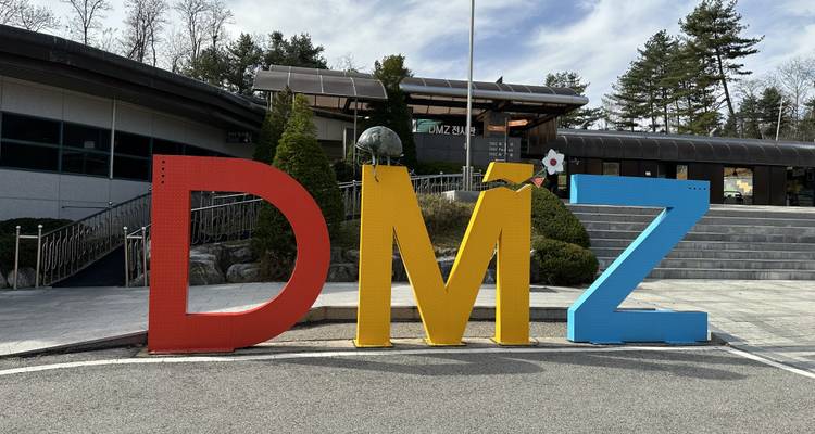 Letras grandes y coloridas de la DMZ fuera de un centro de visitantes bajo un cielo parcialmente nublado.