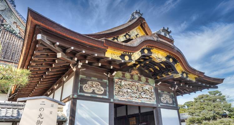 Puerta karamon decorativa con tallas ornamentadas y pan de oro bajo un cielo azul despejado.