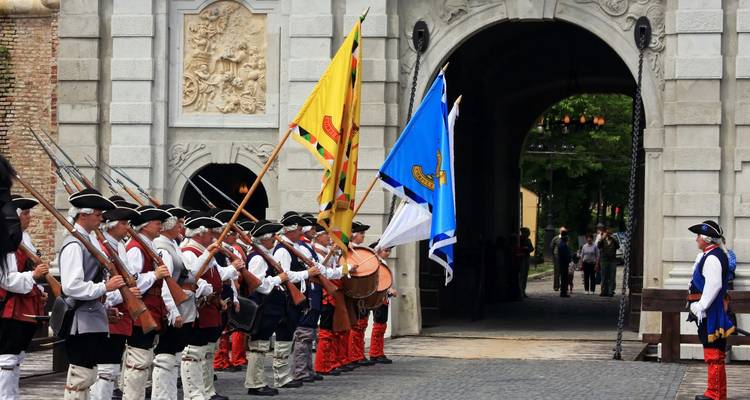 Costumed guards lining up with flags outside the Alba Iulia citadel gate during a re-enactment