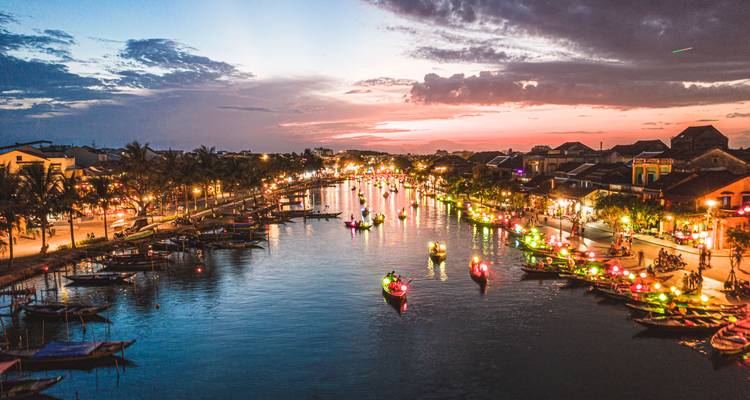 Twilight aerial of Hoi An Ancient Town river sparkling with colorful lantern boats and warm waterfront lights.