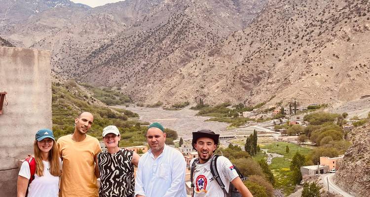 Small group of travelers posing in front of a rugged Atlas Mountains valley landscape.