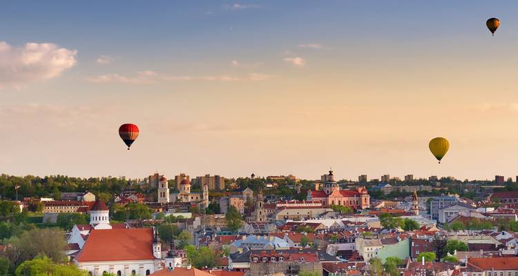 Les montgolfières survolent le ciel aux couleurs pastel de la Vieille Ville de Vilnius au coucher du soleil