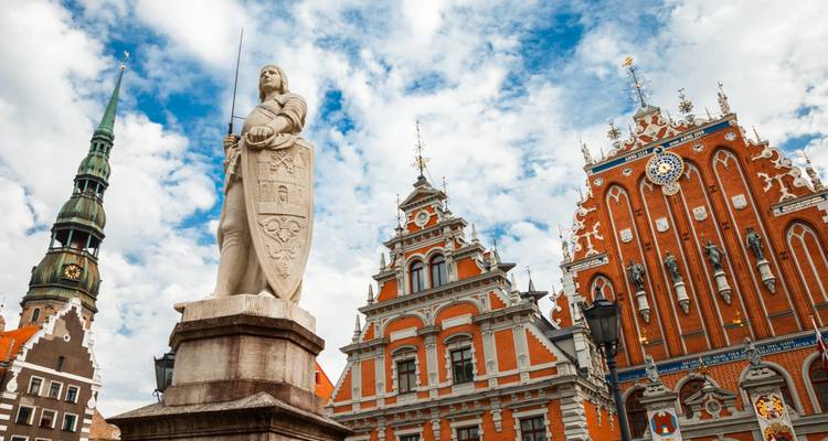 La Statue de Roland se dresse devant les ornées maisons de corporations en briques rouges et le haut clocher de l'église à Riga.