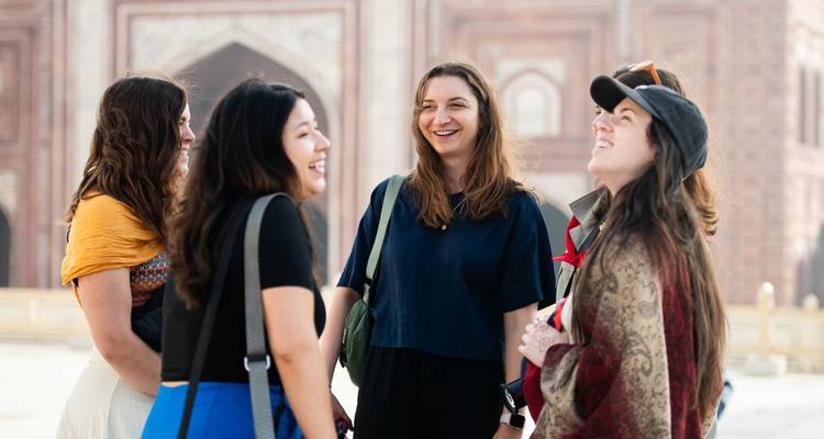 Group of travellers laugh together outside a grand red-sandstone gateway in Agra’s Taj Mahal complex.