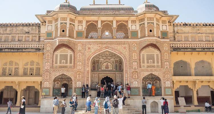Ornately painted Ganesh Pol gateway of Amber Fort with visitors gathering at its grand entrance.
