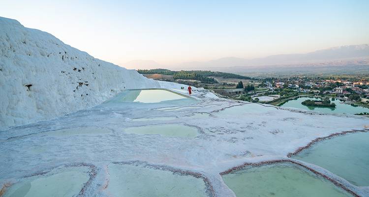Les terrasses blanches de travertin de Pamukkale avec ses bassins turquoise surplombent la vallée lointaine au crépuscule.