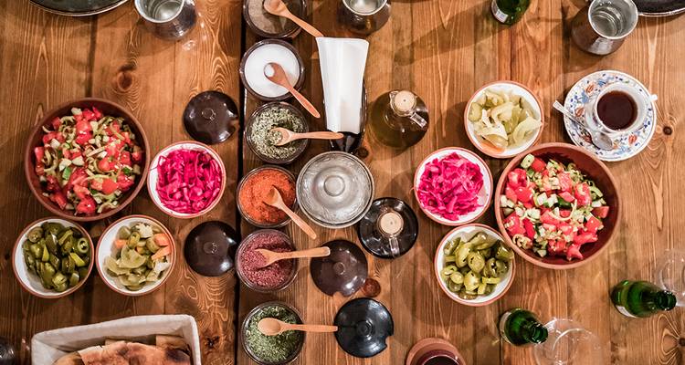 Vue de dessus de salades turques colorées, de cornichons et de thé sur une table en bois rustique.