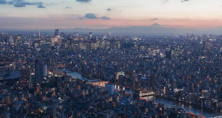 Schemering panorama van Tokio's uitgestrekte skyline met rivieren, wolkenkrabbers en silhouet van de verre Mt. Fuji.