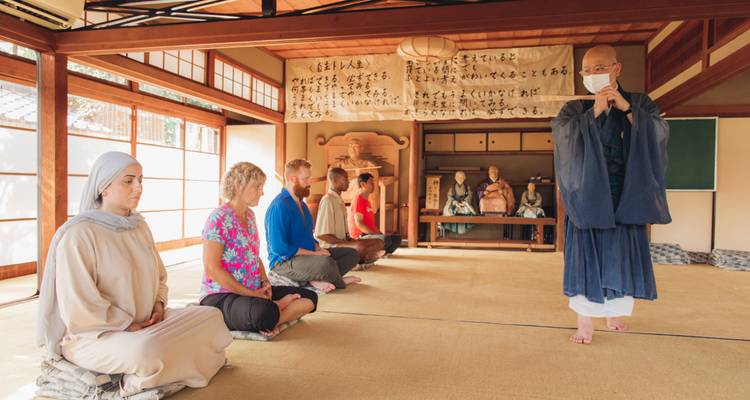 Meditatiesessie in een tempeltuin met tatami-vloer onder leiding van een monnik in traditionele gewaden.
