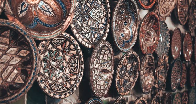 Exhibición de cerca de platos de cerámica marroquí pintados de manera intrincada colgando en una pared.