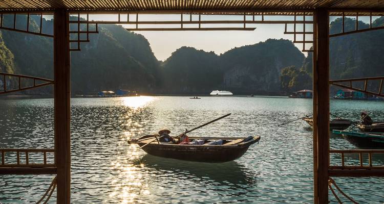 Traditionele houten roeiboten drijvend op turquoise water omgeven door kalksteenrotsen bij zonsondergang