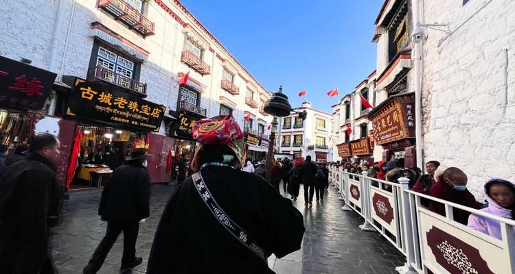 Busy traditional Tibetan street lined with whitewashed buildings and colourful shop signs crowded with locals and visitors.