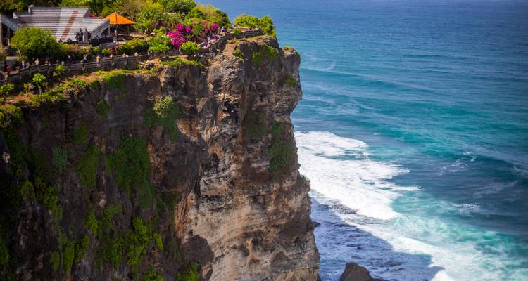 Dramatische Meeresklippen, die in Uluwatu mit Grünflächen bedeckt sind und türkisfarbene Wellen überblicken.