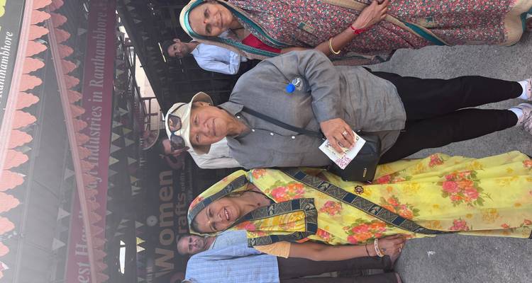 A tourist smiles alongside local women dressed in bright saris outside a handicraft centre in Rajasthan.