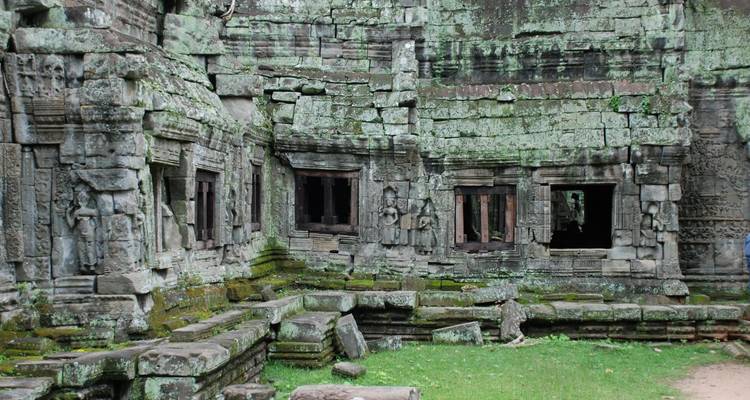 Mit Moos bewachsene Steinmauern und geschnitzte Fenster in einer Tempelruine von Angkor.