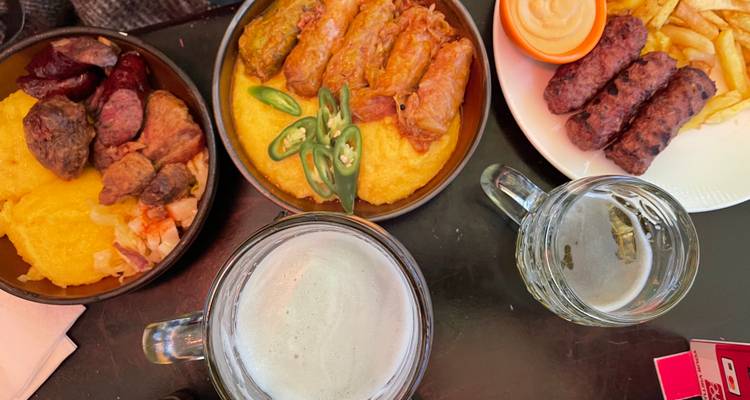 Bovenaanzicht van traditionele Roemeense gerechten met bierpullen op een donkere tafel