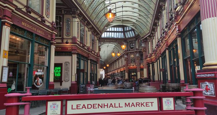 Wide interior view of ornate Leadenhall Market arcade with signage and warm lighting.