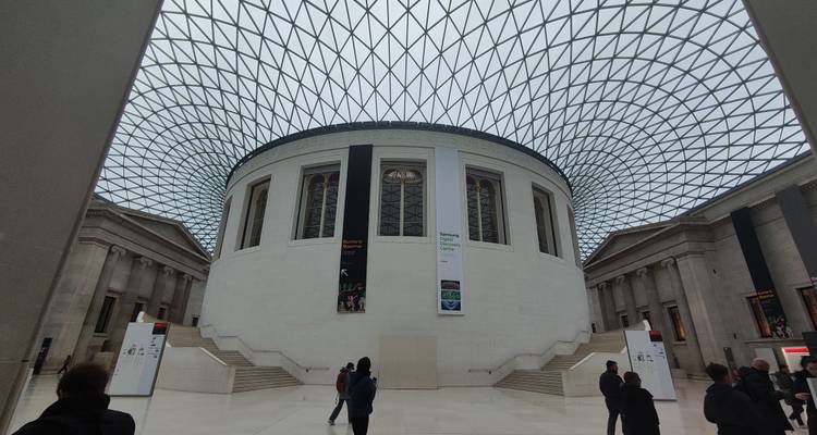 Iconic Great Court of the British Museum with glass-grid roof and visitors on white floor.