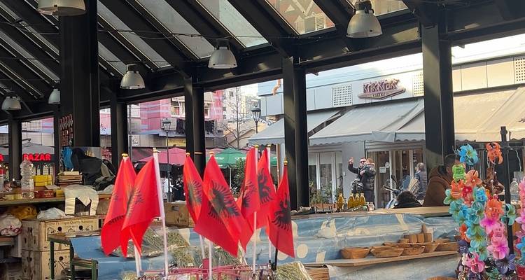Kraampjes met Albaanse vlaggen en houten handwerk in de levendige openluchtmarkt