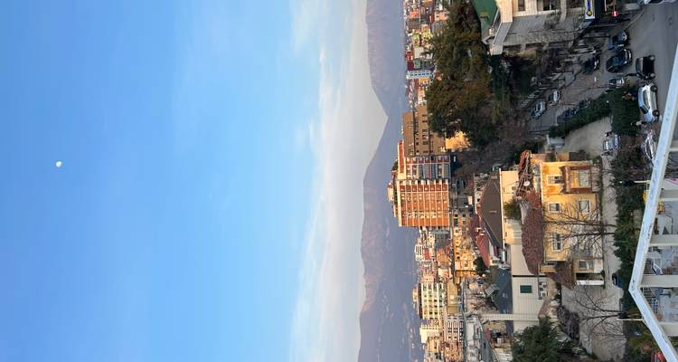 Dakterras panorama van Tirana met omringende bergen en de maan in een heldere hemel