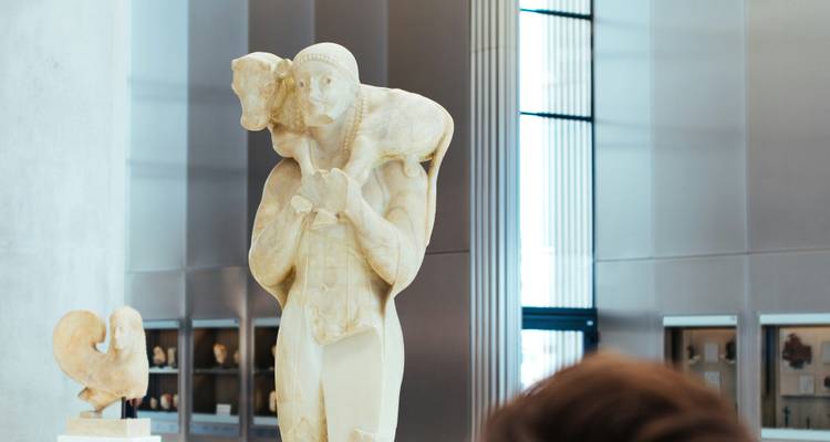 Ancient marble statue displayed inside a modern museum hall with diffused daylight.