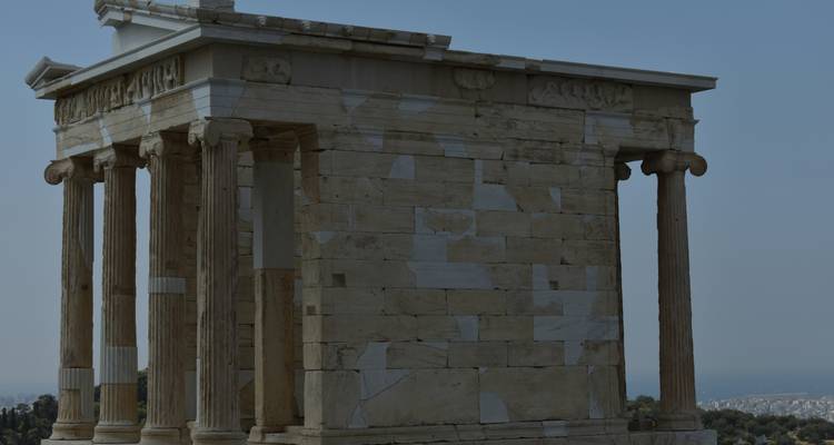 Dimly lit side view of the small marble Temple of Athena Nike against a muted sky.