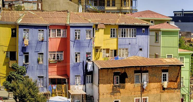 Row of vibrantly painted hillside houses in Valparaiso, Chile under bright daylight.