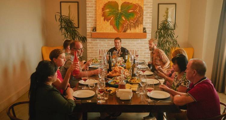 A group of travellers enjoy a plentiful dinner spread around a large indoor dining table.
