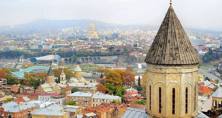 Panoramic skyline of Tbilisi with historic church tower in foreground.