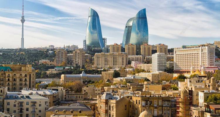 Modern skyline of Baku featuring the Flame Towers above historic buildings.