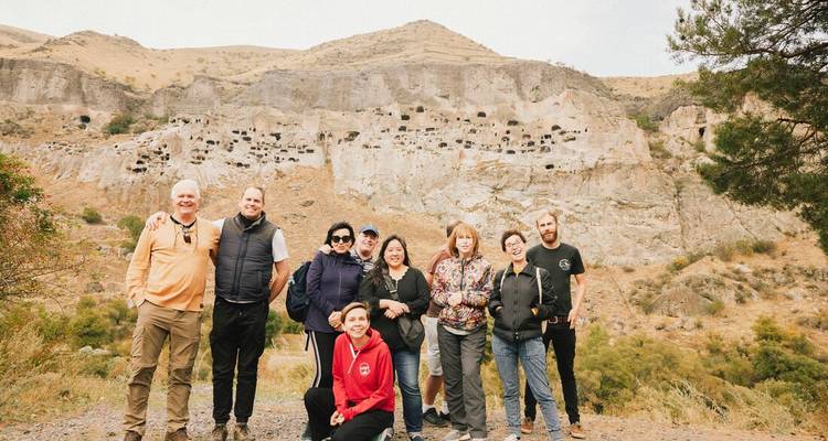 Tour group poses in front of the cliffside caves of Vardzia.