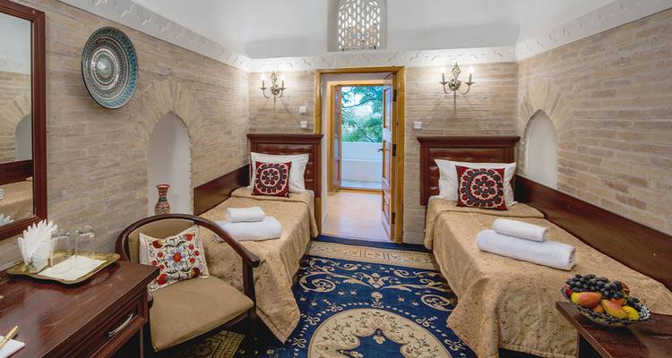 Chambre d'hôtes jumelée charmante dans un caravansérail restauré avec des arcs en briques, des tapis à motifs et des céramiques traditionnelles.
