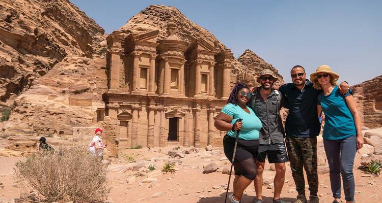 Travelers smile together in front of the monumental Monastery carved into Petra’s sandstone cliffs.